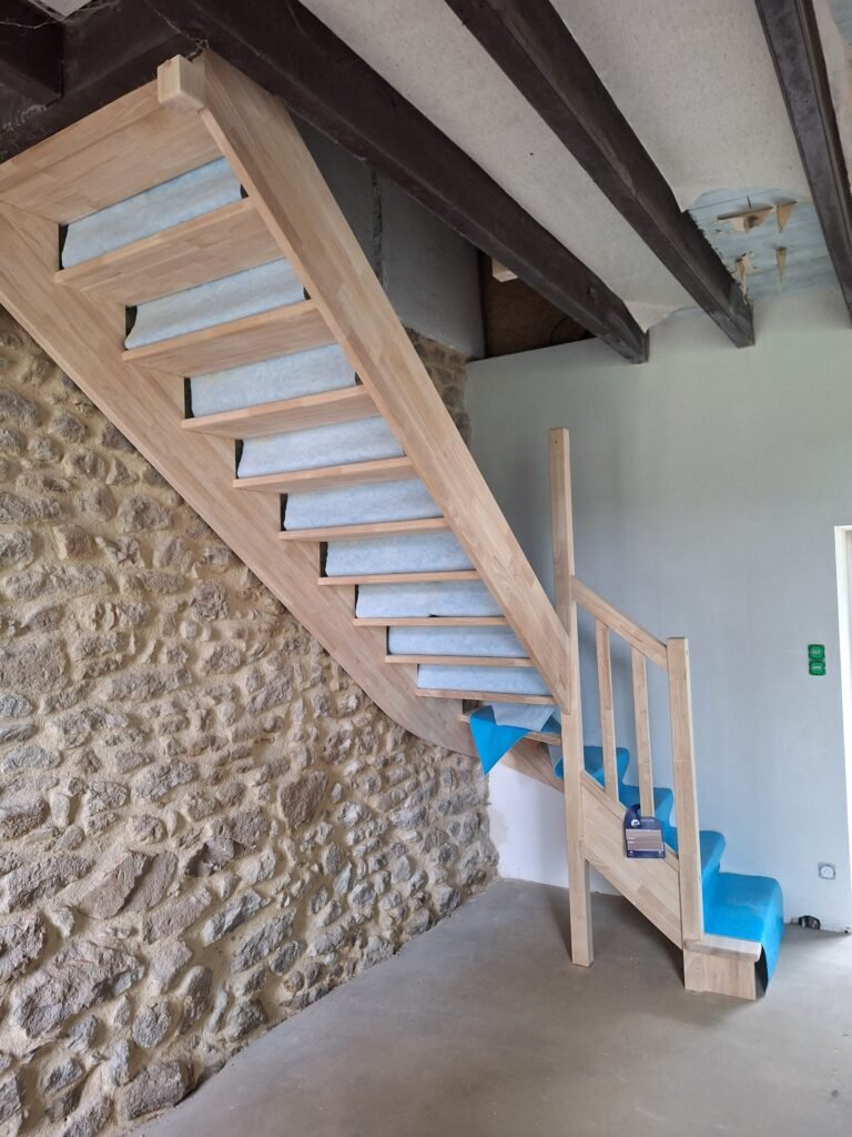 Escalier en bois sur mesure adossé à un mur en pierre dans le Morbihan